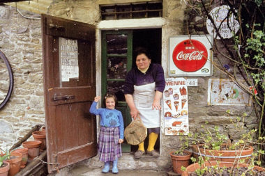 Frau und Kind winken aus einem alten Lebensmittelgeschäft in der Toscana Italien